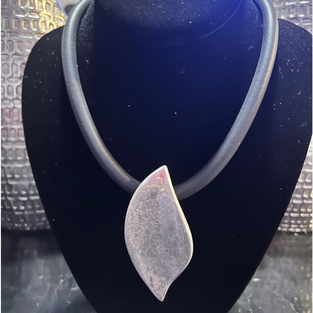 Costume brushed silver charm on rubber necklace.  Steal the show.